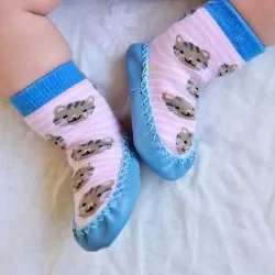 Baby som bär rosa/blå mockasiner med kattmotiv