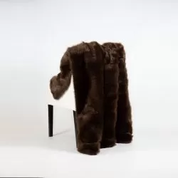 Brun fuskpälspläd hängande över ryggstöd