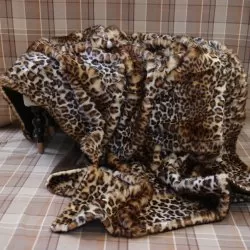 Leopardmönstrad fuskpälspläd över rutigt tyg